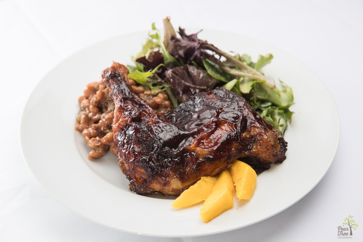 Barbecued chicken with baked beans, spring mix salad, and mango slices made by Divine Taste of Heaven.
