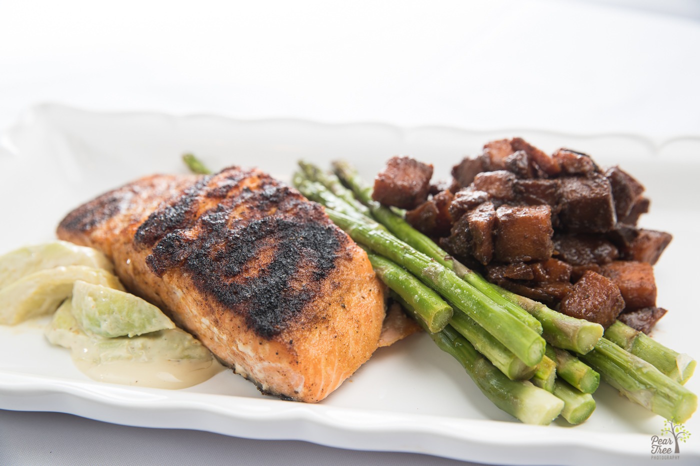 Blackened salmon with fresh asparagus, potatoes, and creamy avocado slices prepared by Divine Taste of Heaven.