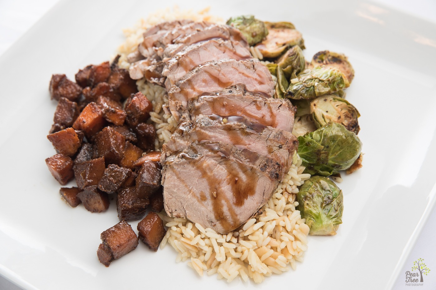 Pork tenderloin on a bed of rice served with roasted potatoes and brussell sprouts prepared by Divine Taste of Heaven.