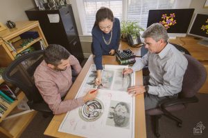 Three landscaping architects working on blueprints together at Manley Land Design office