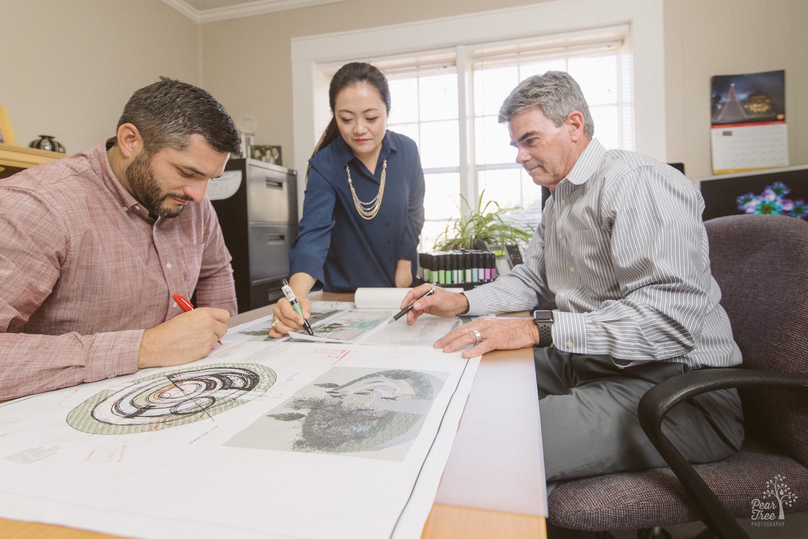Team of three landscape architects working together on blueprints in Manley Land Design office.