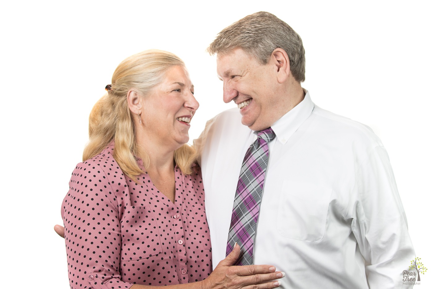 Husband and wife holding each other close and laughing at each other.