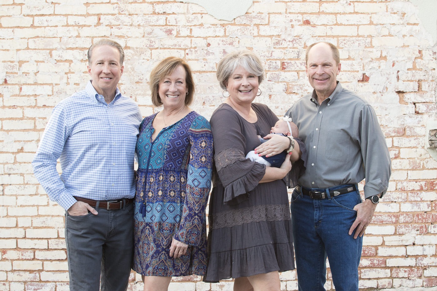 Two sets of happy grandparents holding their newborn granddaughter in downtown Woodstock.