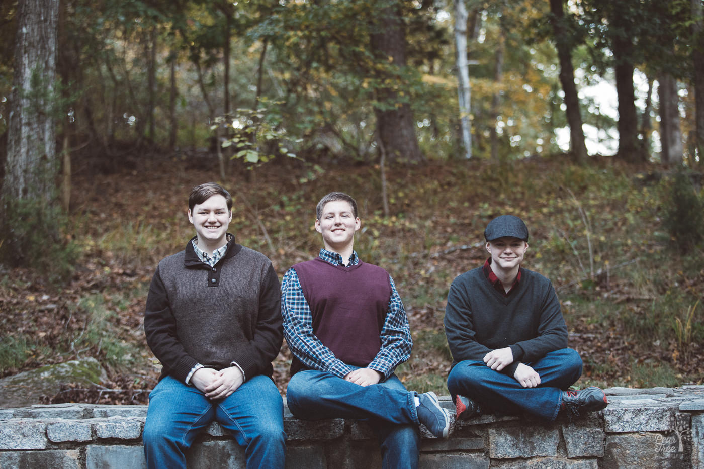 Three teenage brothers sitting together on Stone Mountain wall pretending to be pleasantly serious.