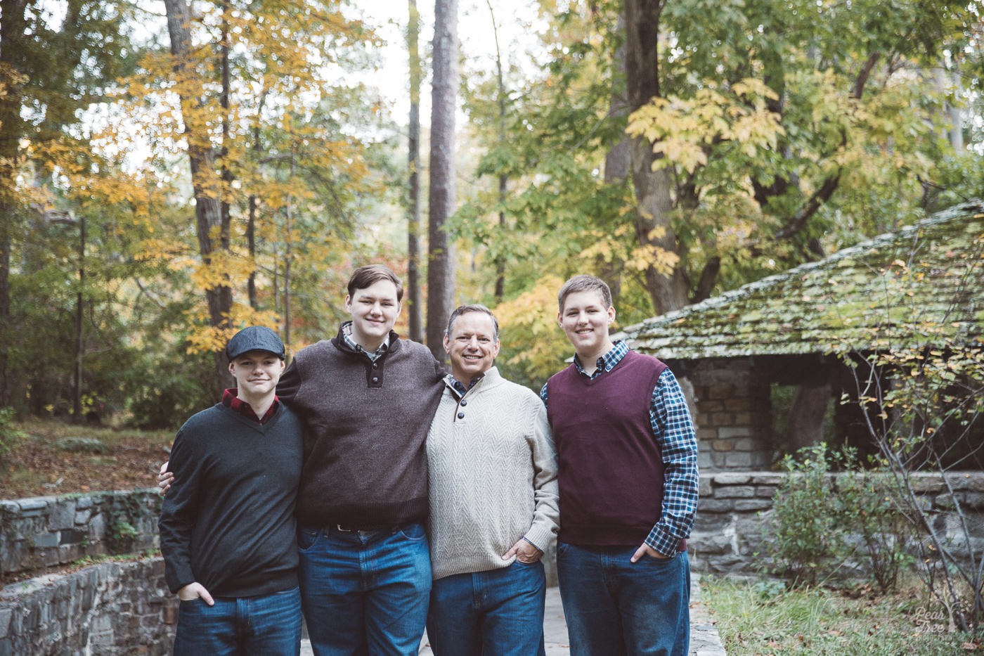 Dad standing with his three teenage sons in front of Stone Mountain pavillion in the fall.