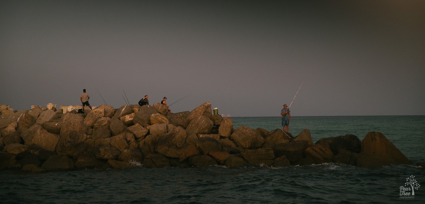 Fishermen on rocks at sunset in Destin, FL.