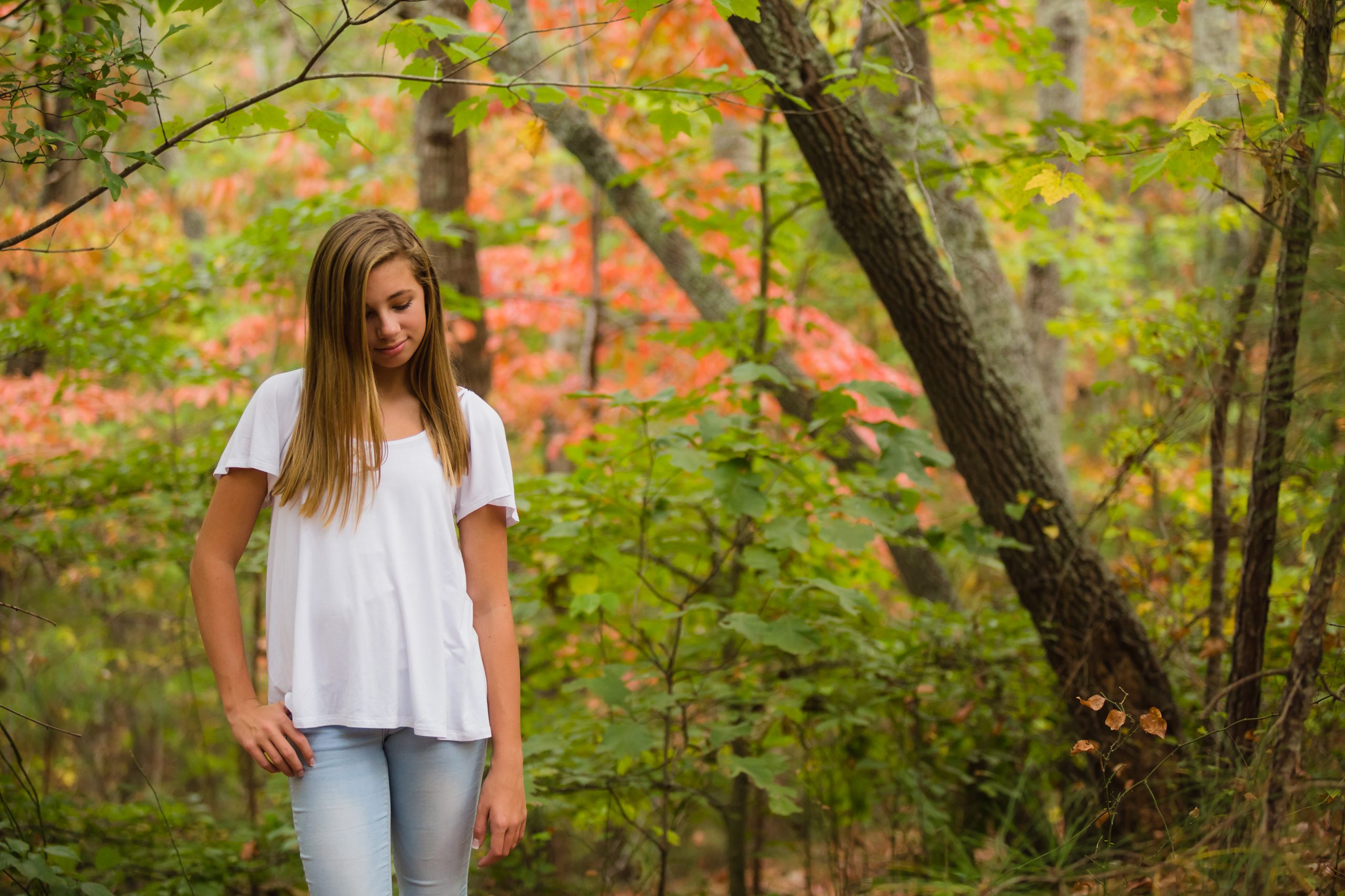 Teenage girl walking in woods with fall foliage