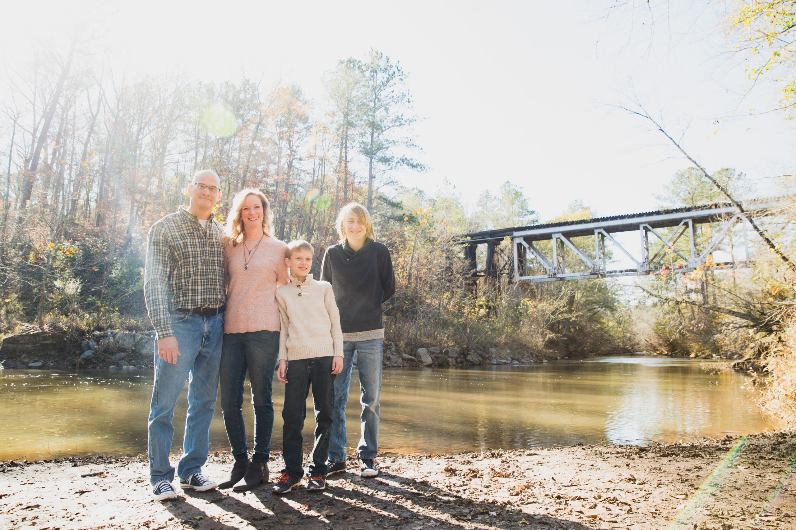 Family with two teenage boys standing in front of Little River and Rope Mill train trestle