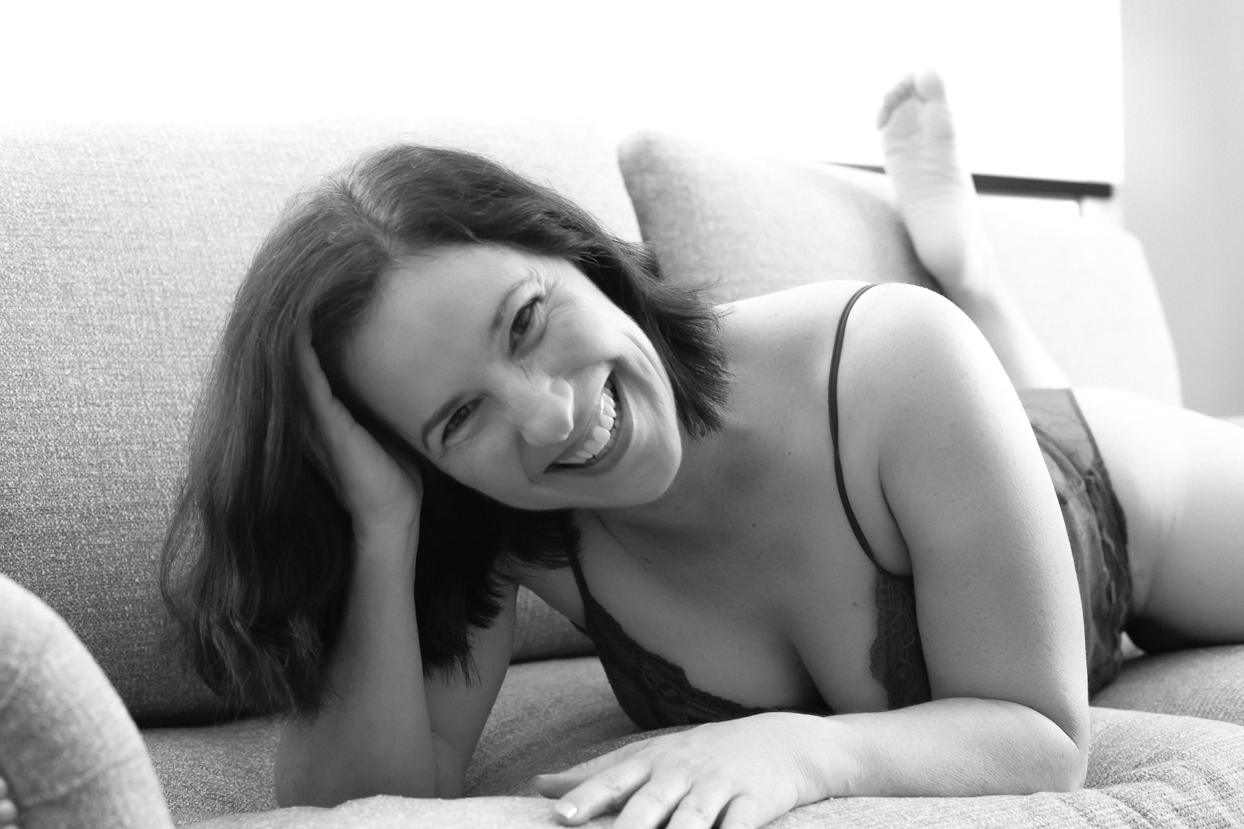 Laughing brunette laying on her stomach with feet up behind her