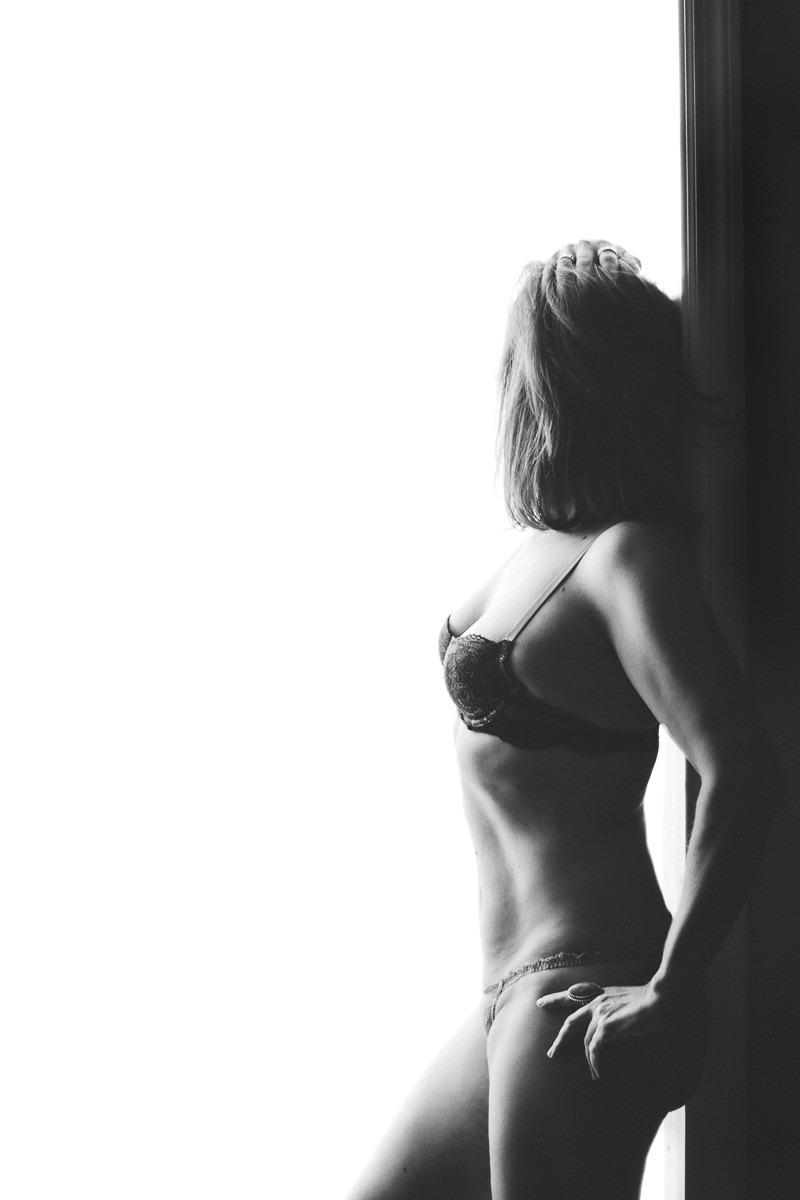 Fit woman standing in doorway looking away wearing only bra and underwear with a big ring on her index finger