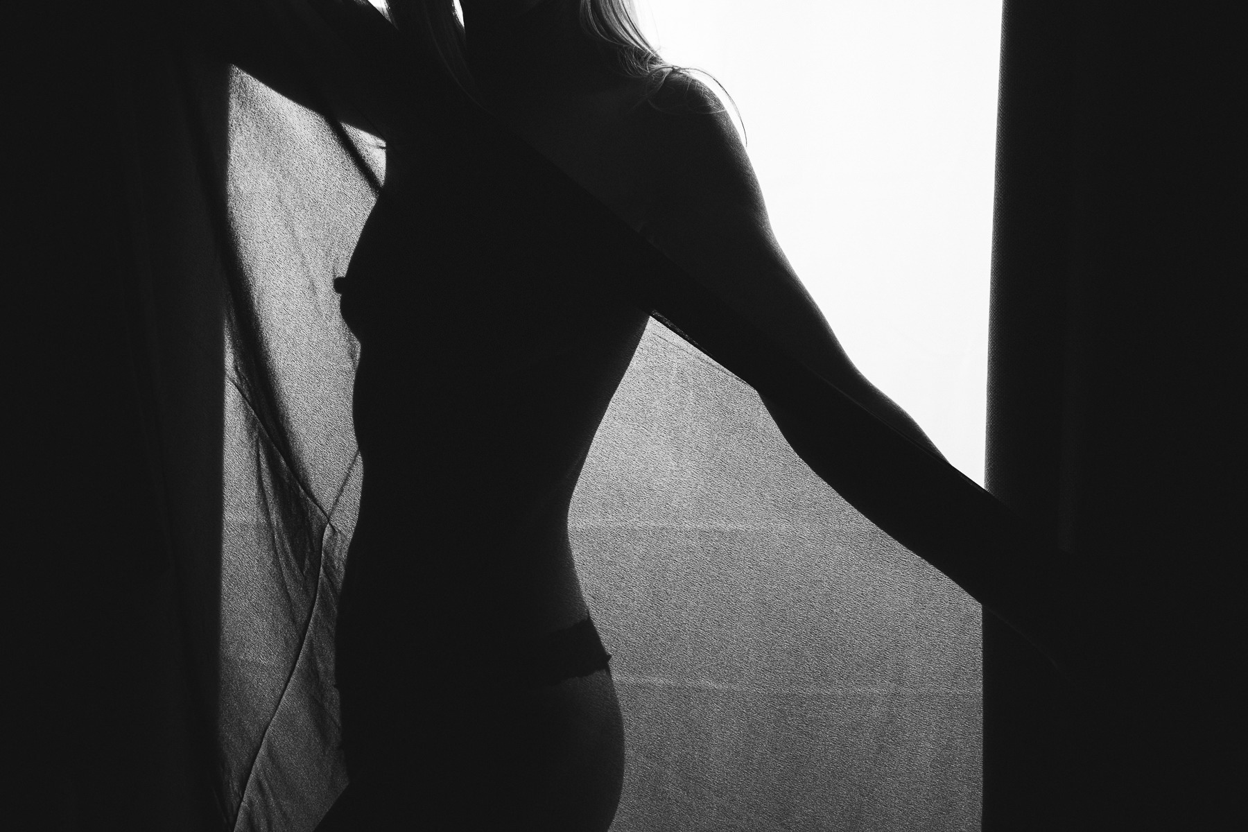 Black + white silhouette of a nude woman through a black sheer scarf