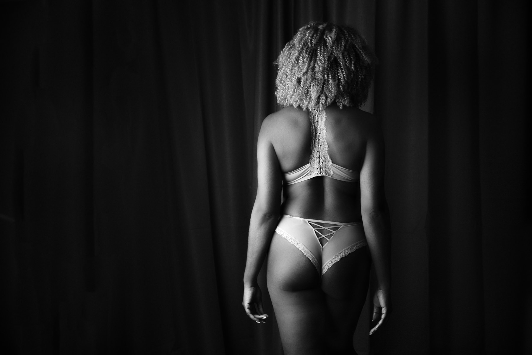 Black and white photograph of an athletically toned black woman wearing lingerie for a boudoir session