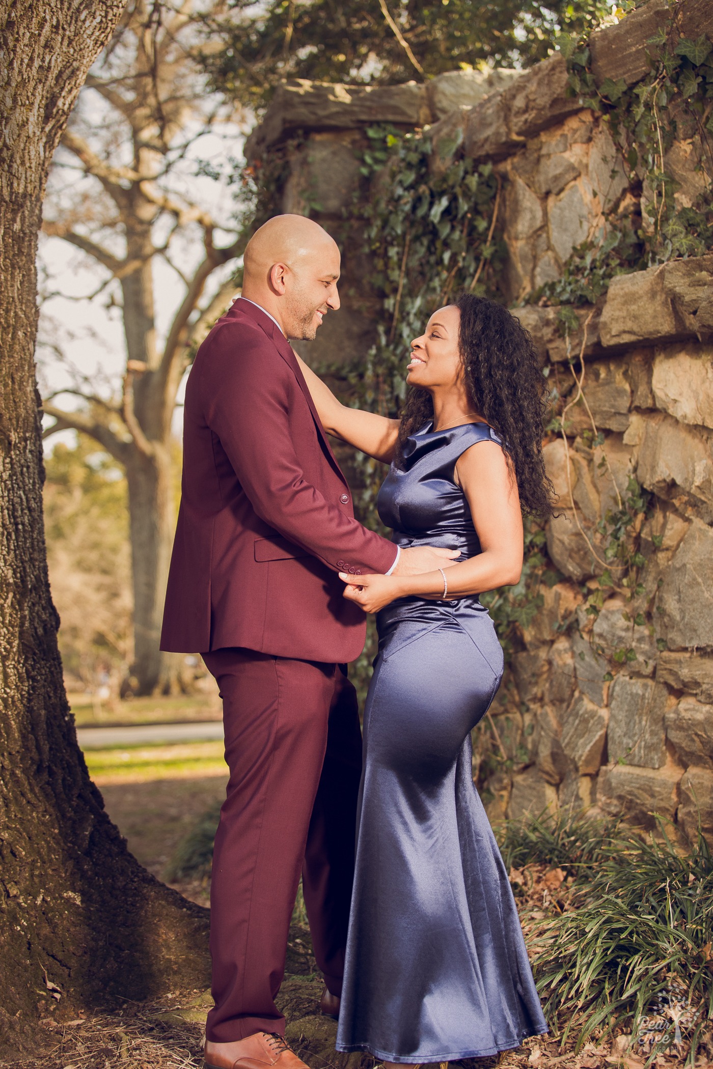 African American couple holding each other and smiling while wearing a fancy suit and gala dress to celebrate their wedding anniversary.