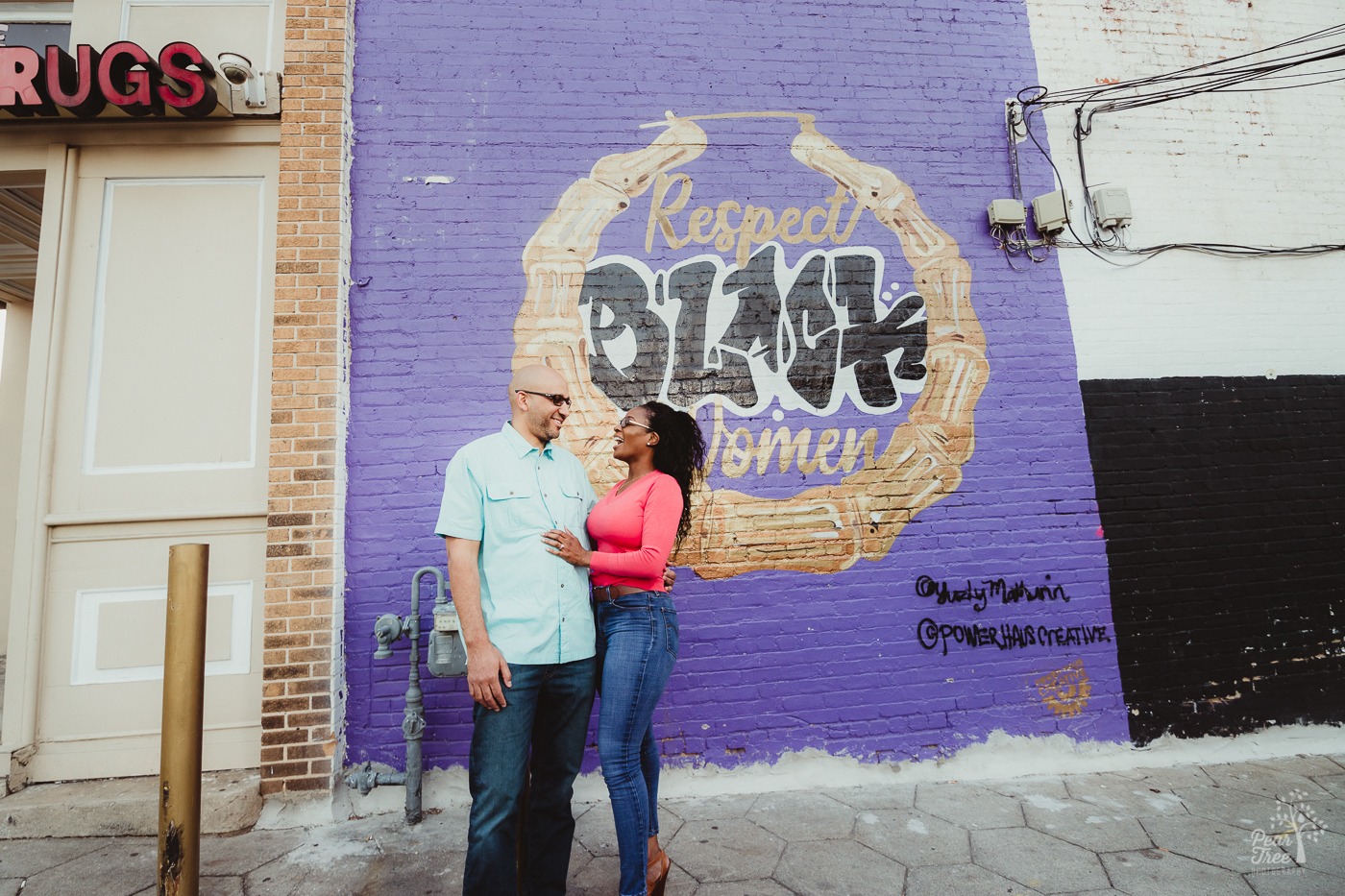 African American couple wearing jeans and sunglasses, having a good time in front of Atlanta mural that says Respect BLACK Women.