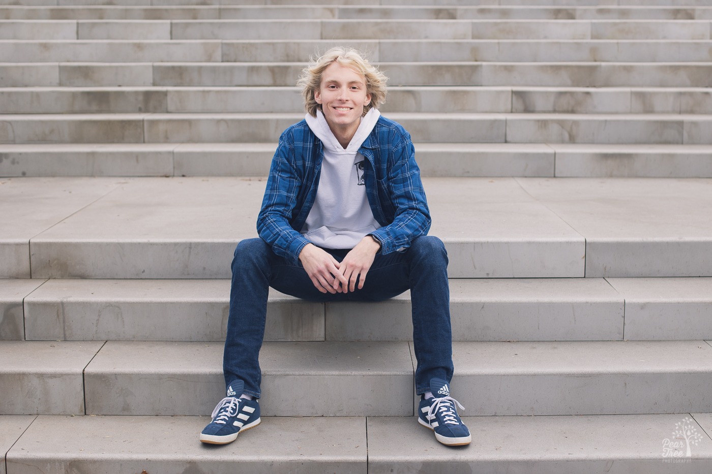 Blond high school boy sitting on white stone steps and smiling