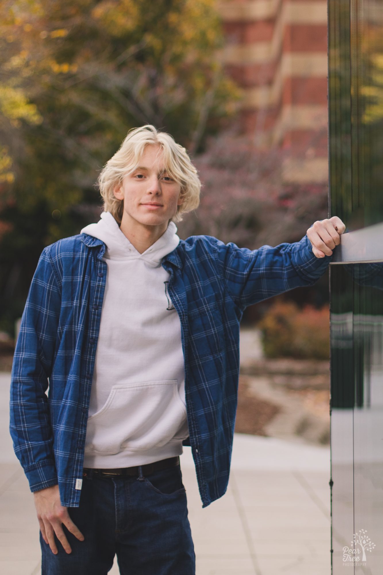 Blond high school senior boy smiling at camera while leaning against glass corner of Tennessee Aquarium