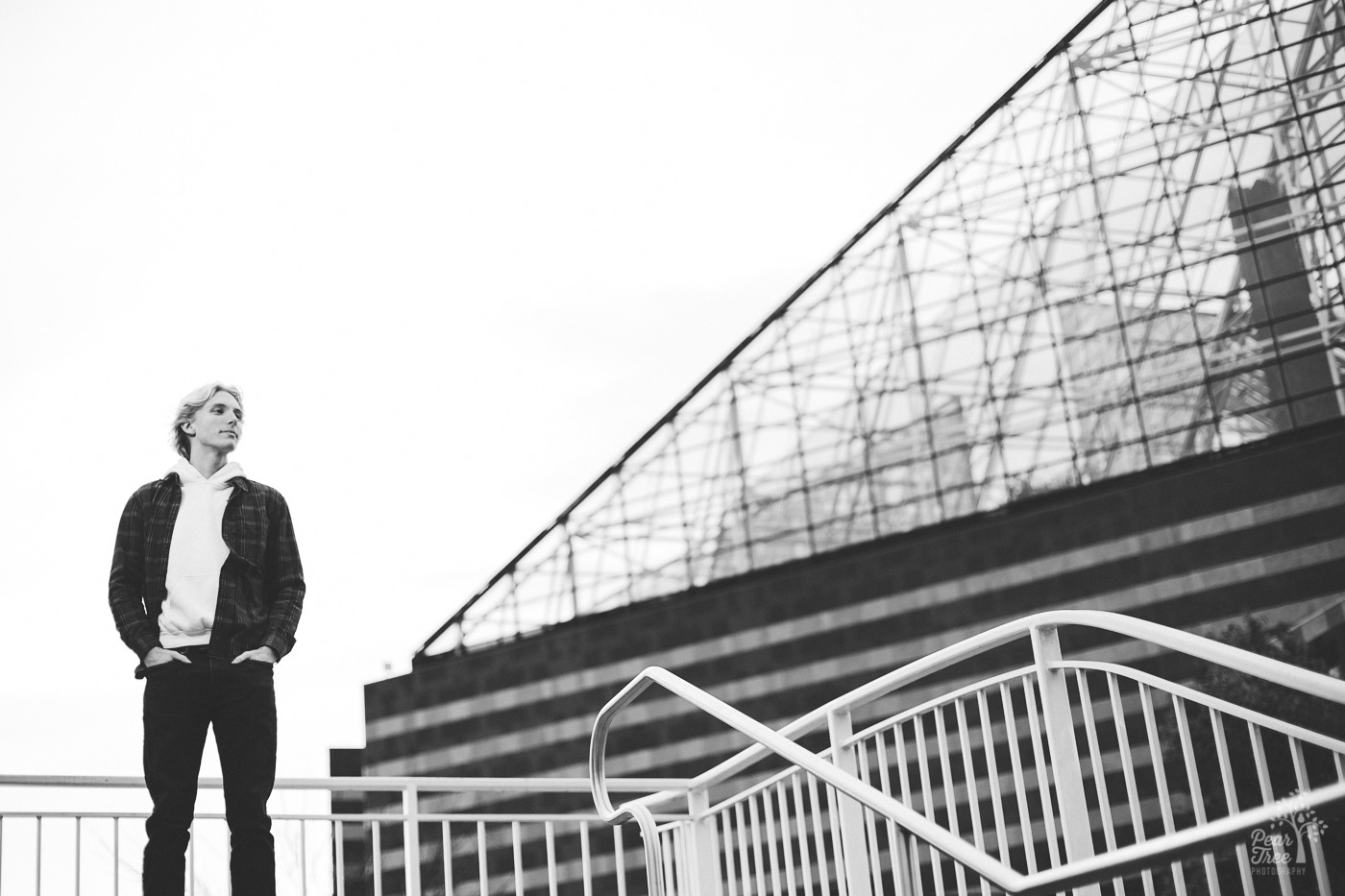 Black and white photograph of high school senior boy standing with Chattanooga pyramid building behind him