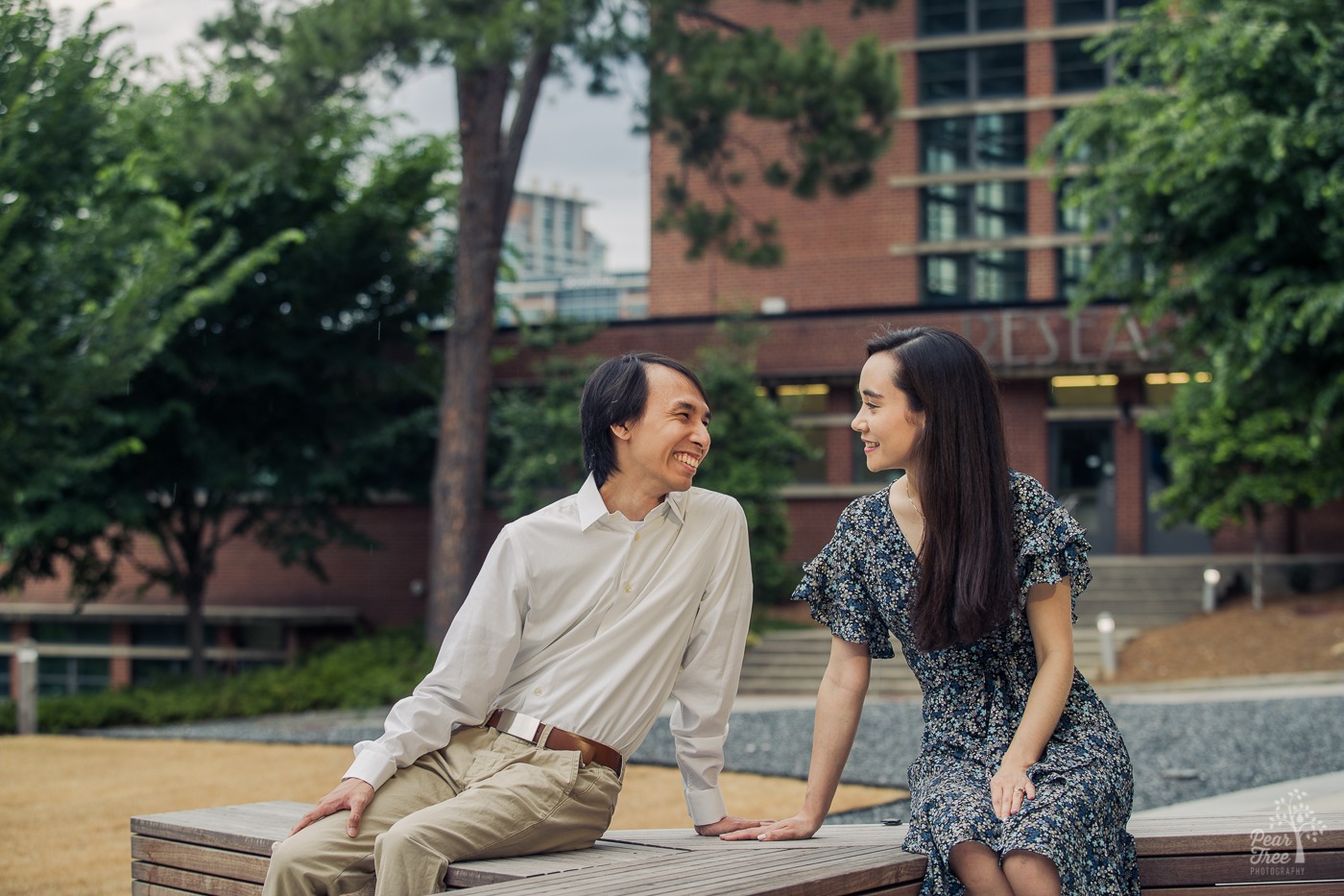 Smiling couple looking at each other with Georgia Tech campus behind them during their engagement photography session