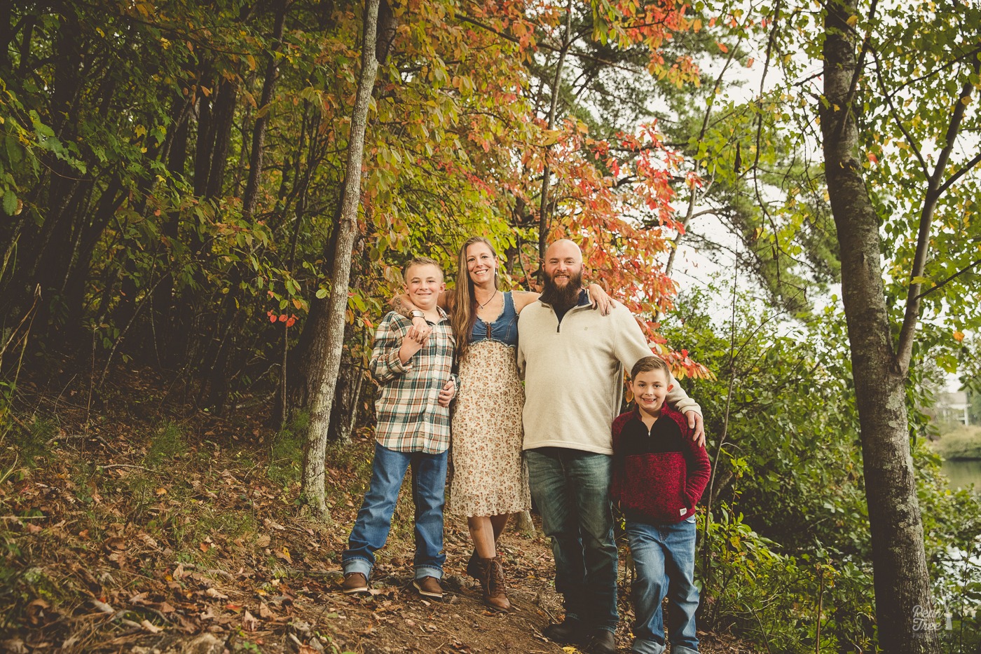 Happy family of four standing in front of fall trees