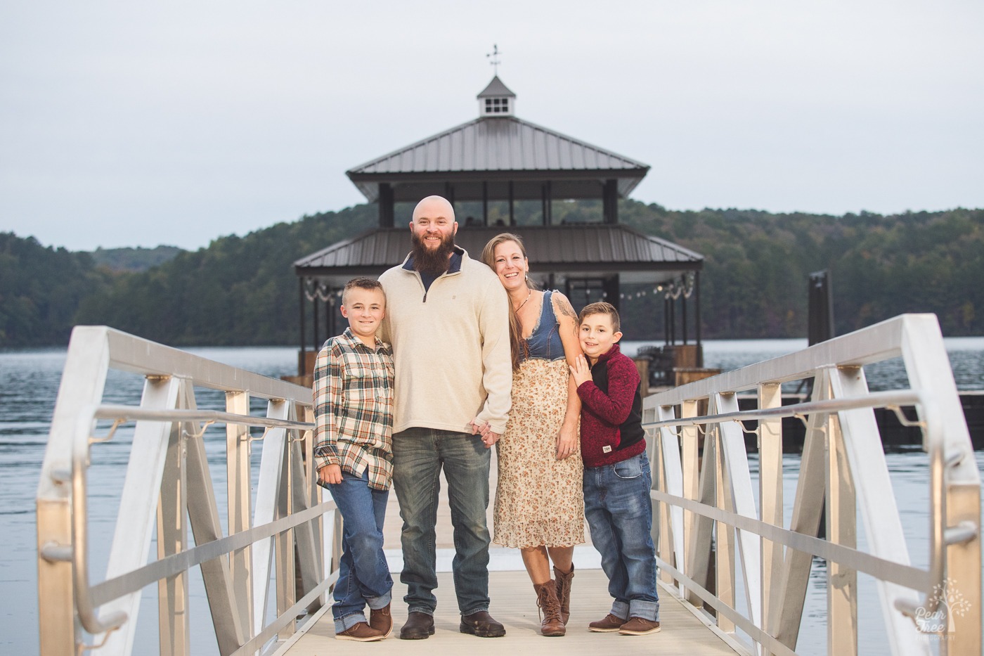 Mom and Dad holding hands while flanked by their smiling young sons on gangway leading to a gazebo on Lake Arrowhead