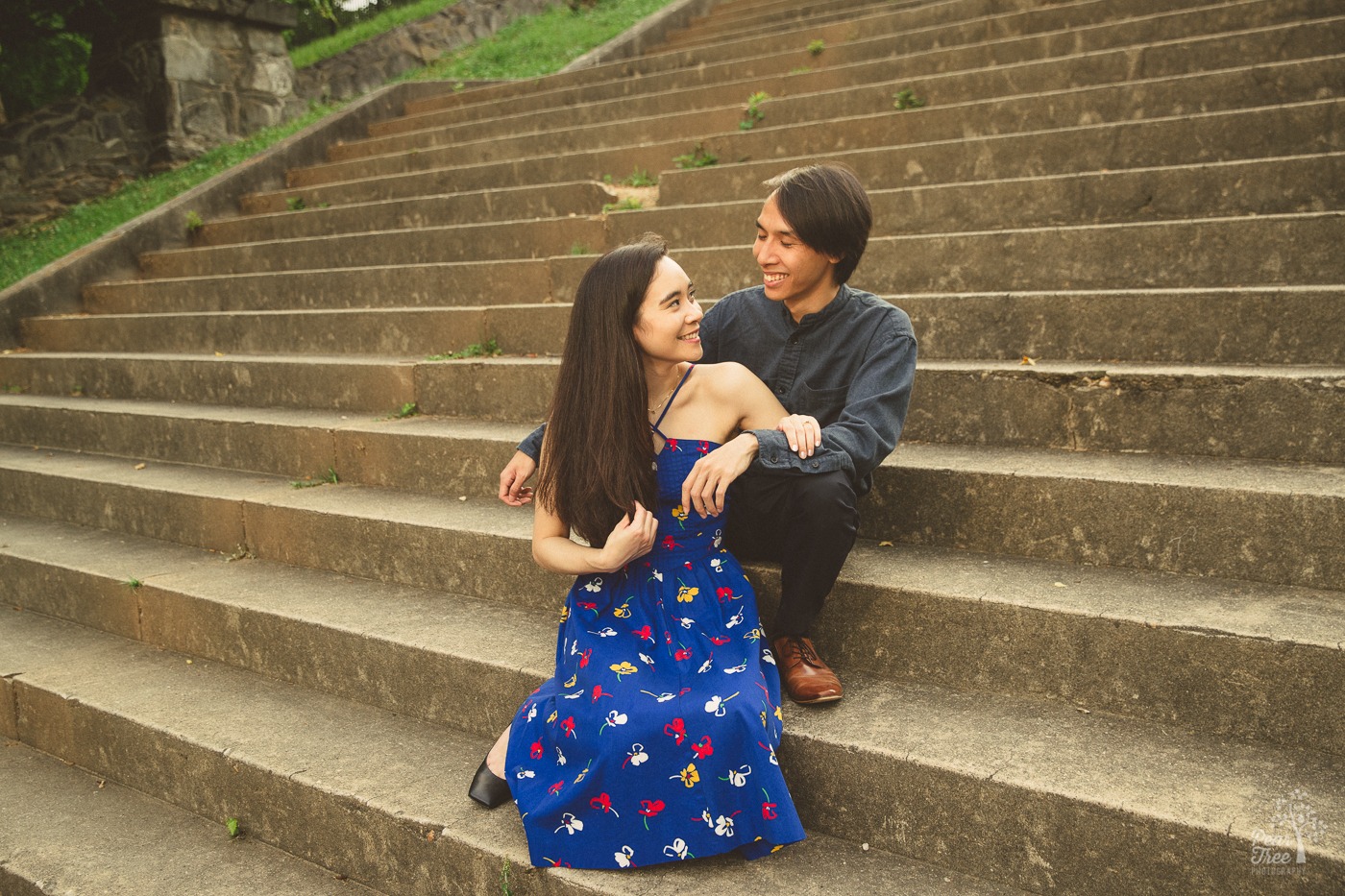 Happy engaged couple sitting on steps in Piedmont Park holding each other