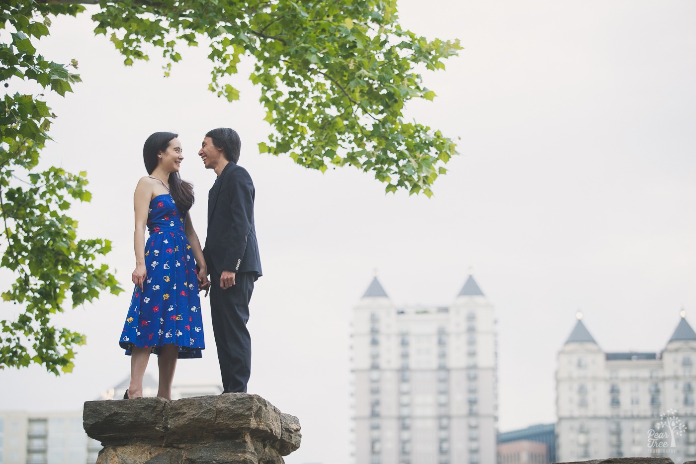 Happy couple holding hands and laughing with Atlanta skyline behind them