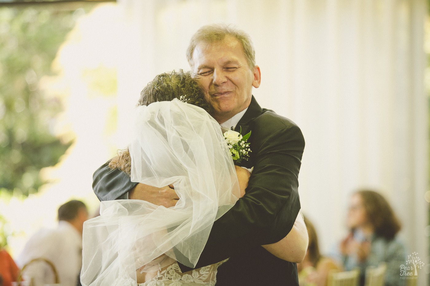 Proud father squooshes his face as he hugs his daughter tight after the Father Daughter dance in Atlanta wedding