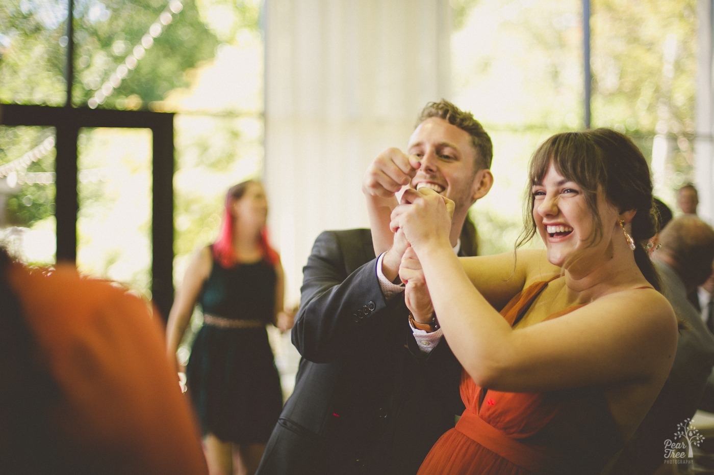 Two members of an Atlanta wedding party are dancing and reeling in another dancer while laughing