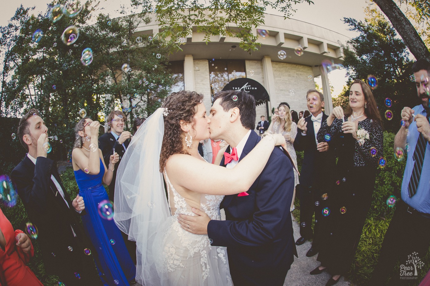 Atlanta wedding couple kisses in the middle of hundreds of bubbles at their exit outside of The Atrium