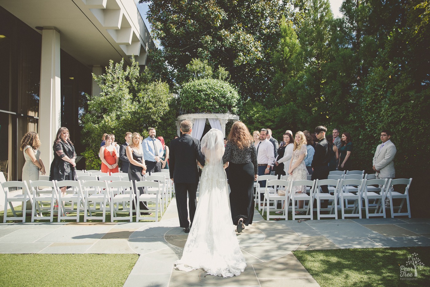 Father and mother walking their daughter down the outdoor wedding aisle at The Atrium in Norcross