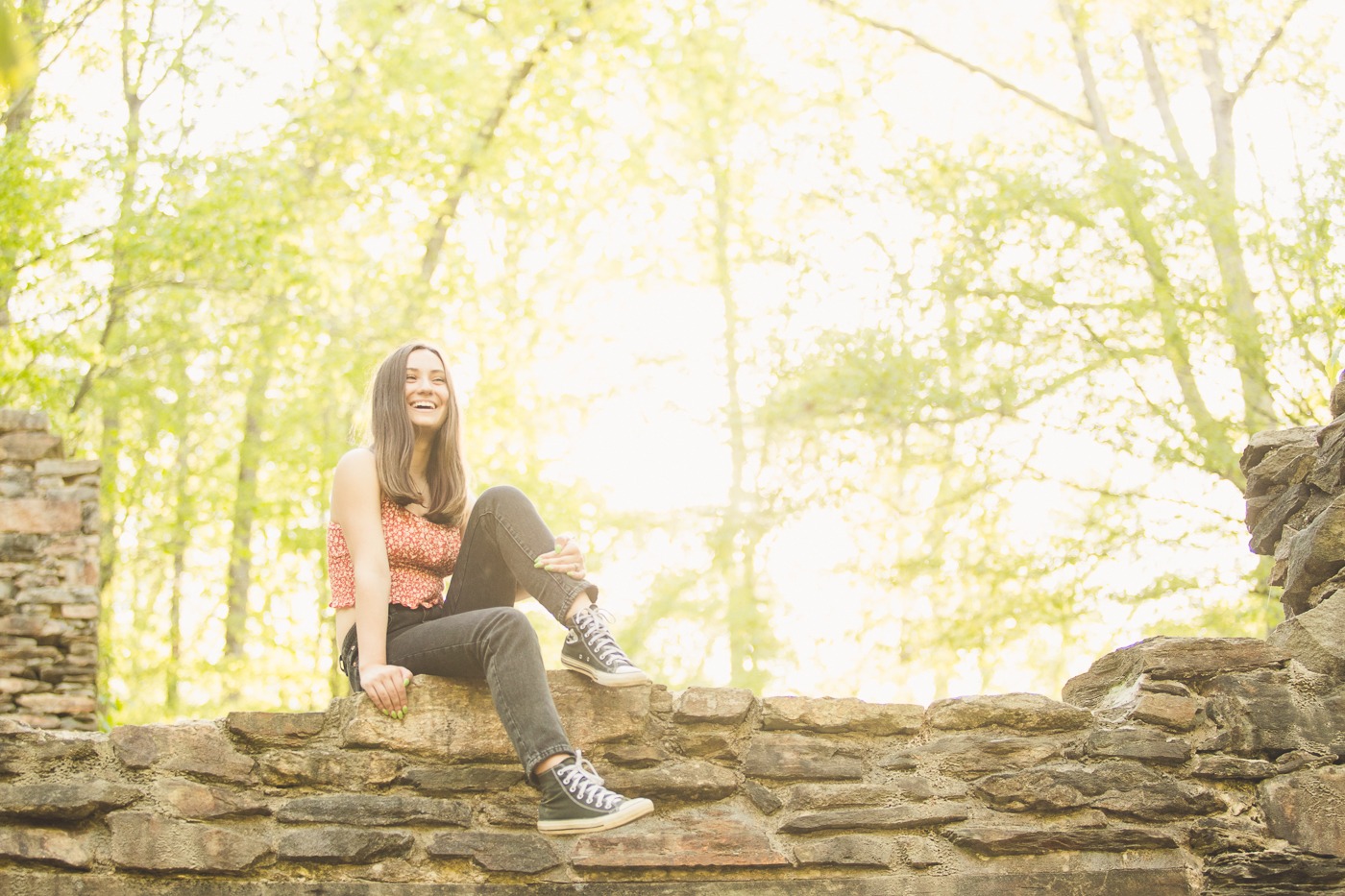 Laughing teenage girl sitting on top of an old stone building