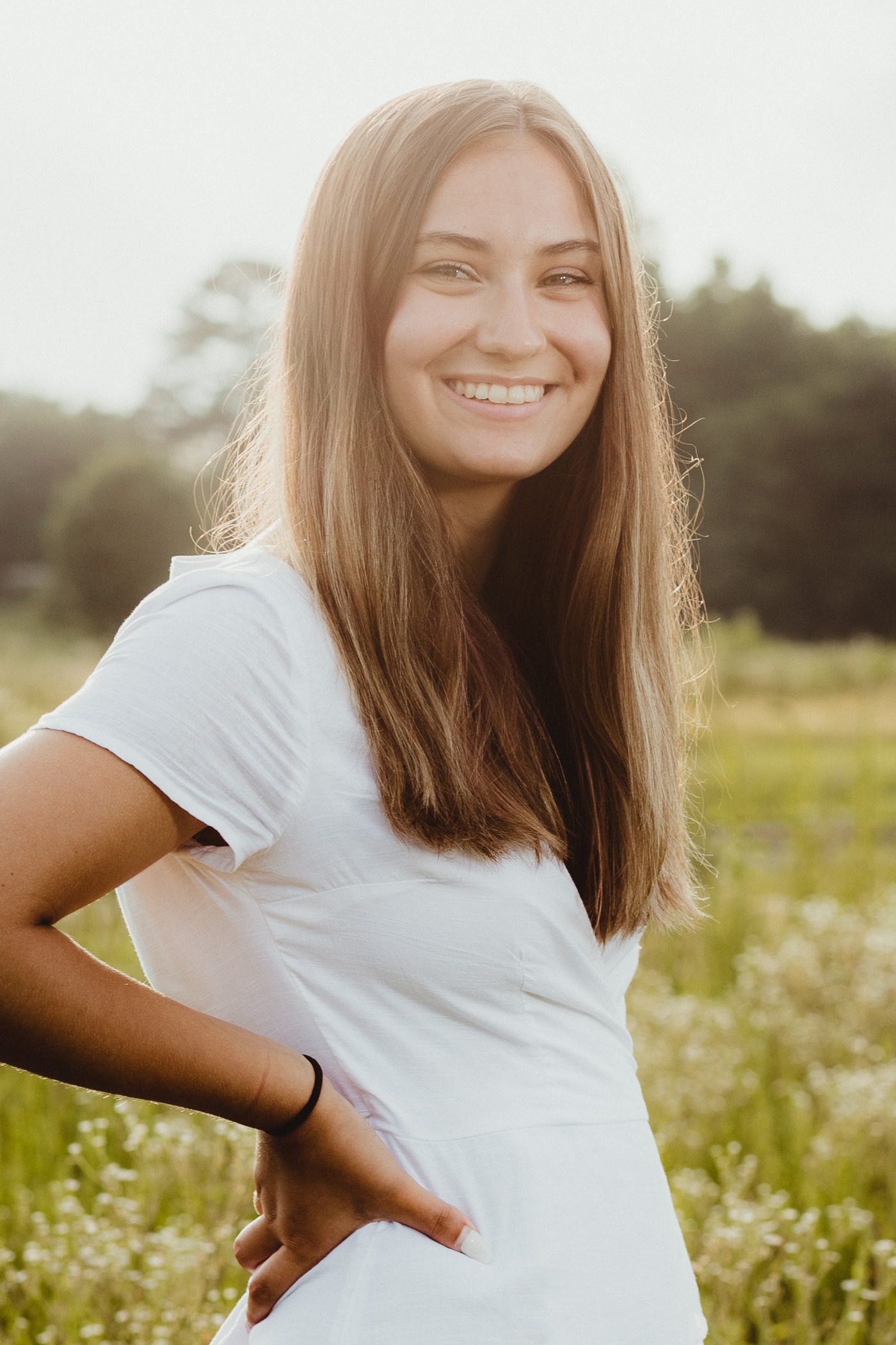 Smiling teenage girl in a white dress with the sun shining on her hair