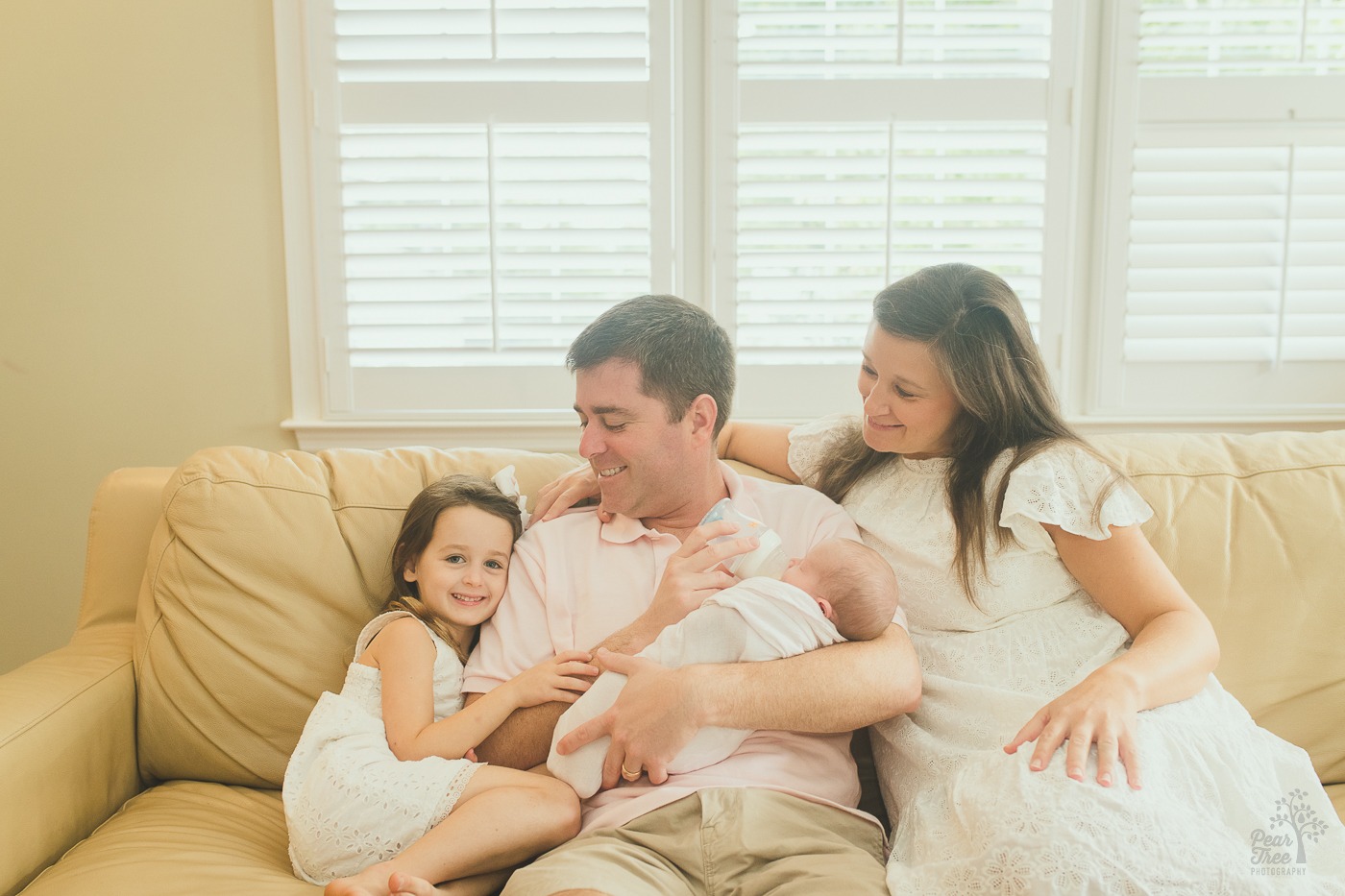 Sweet parents holding their newborn daughter and smiling at their older daughter