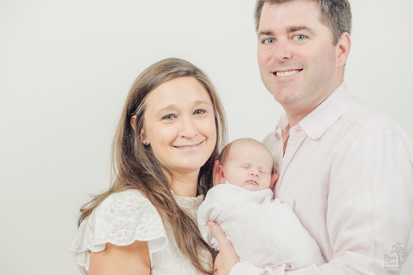 Mom and dad smiling and holding their newborn daughter close