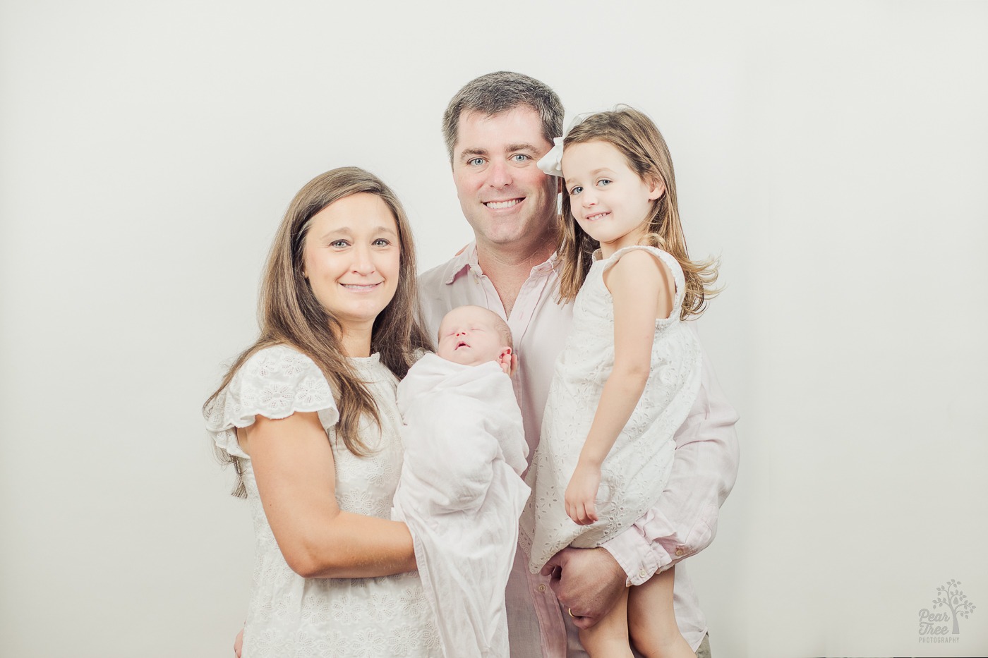 Mom and dad holding their daughters for newborn photographs