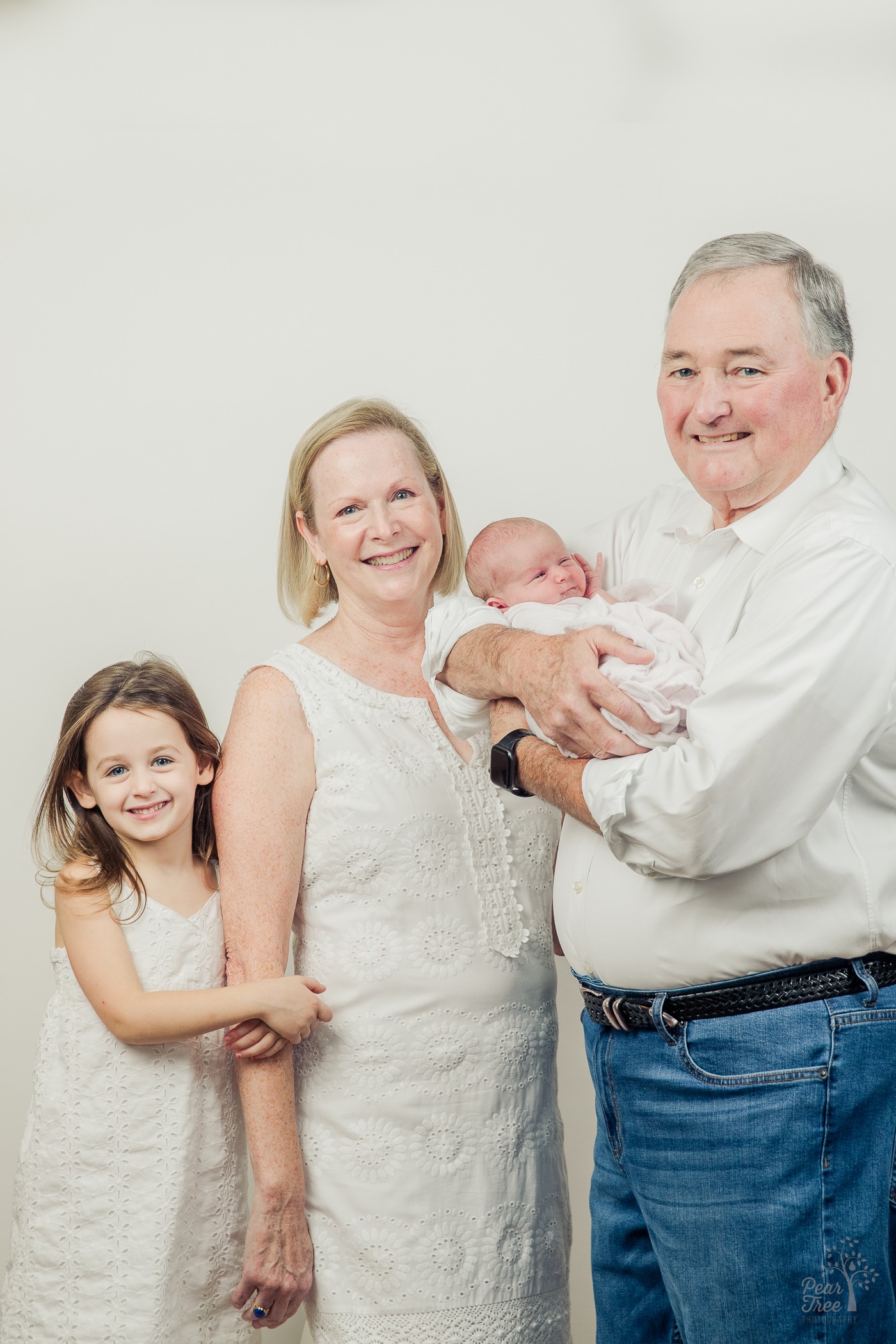 Grandparents smiling for newborn photographs with their two grand daughters