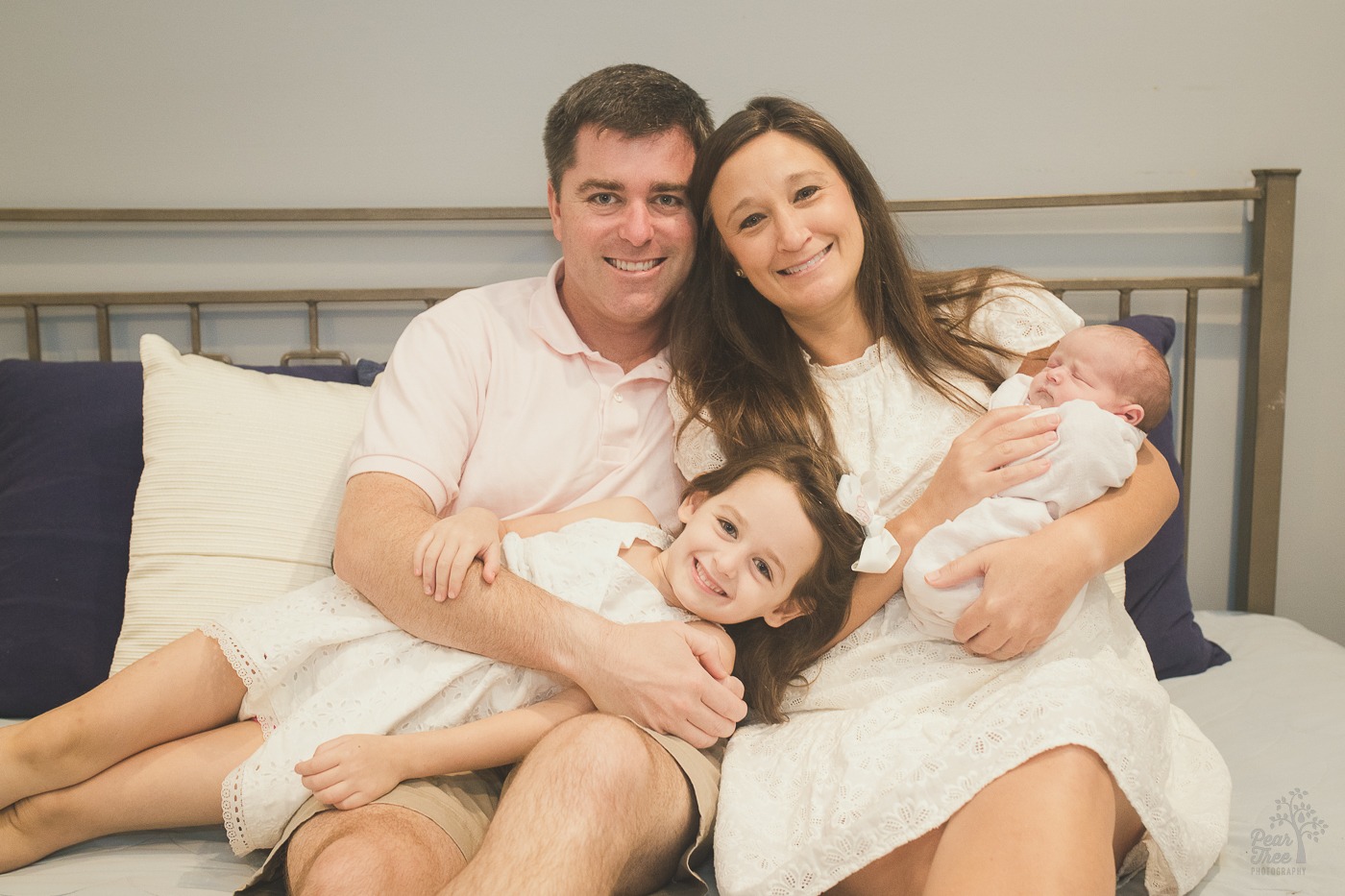 Cute family lounging on their master bed with newborn baby daughter