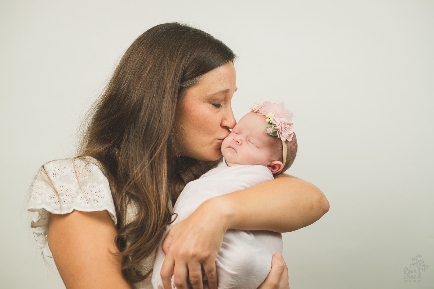 Mom holding her baby daughter and kissing her cheek for newborn photographs