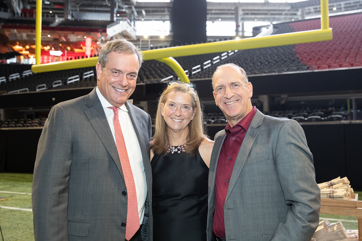 Sandy and Jessica Douglas standing with Neil Berg under the goal post at Mercedes Benz stadium. Before Covenant House Georgia's 2021 Night of Broadway Stars event