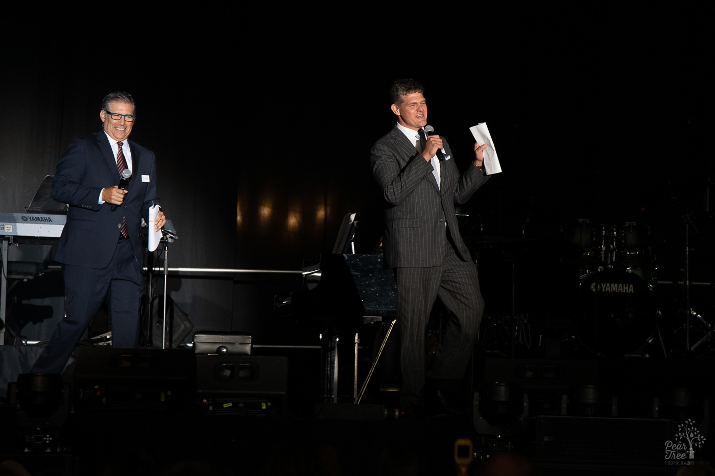Ben Deutsch and Clark Dean on stage before Night of Broadway Stars 2021 event. They are talking to Covenant House Georgia supporters sitting on the Mercedes Benz stadium field