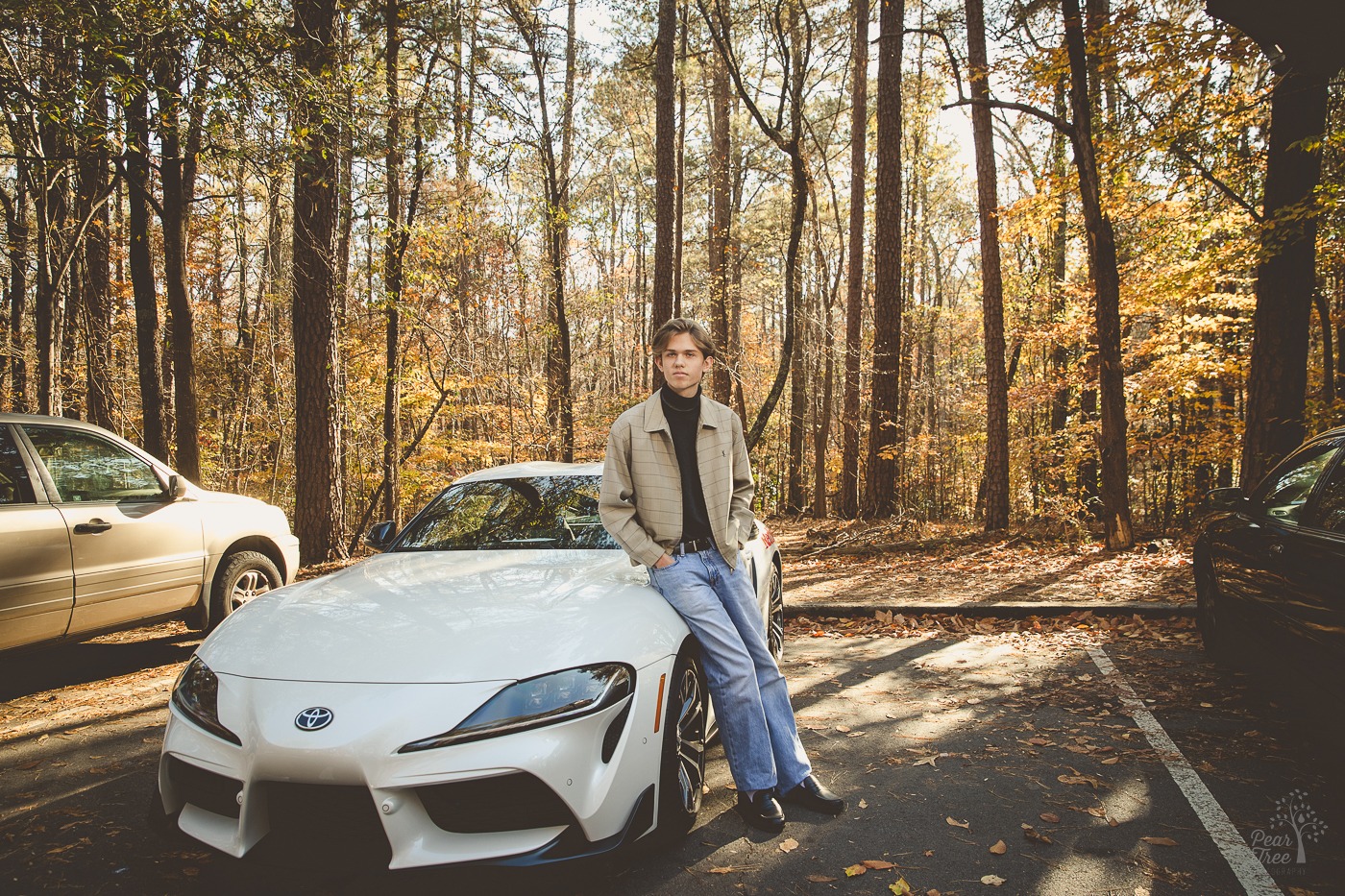 Canton high school senior boy leaning on his car in front of fall leaves