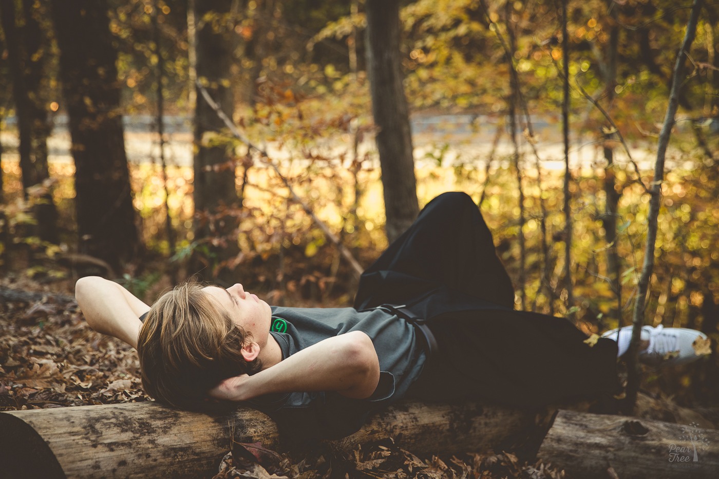 Canton high school senior boy laying on a fallen tree with his hands under his head