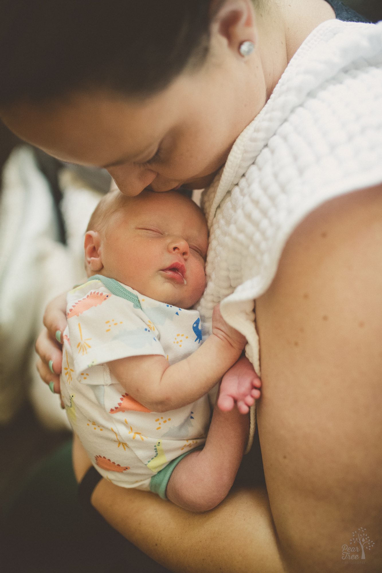 Mom kissing her son's head during their newborn photography session