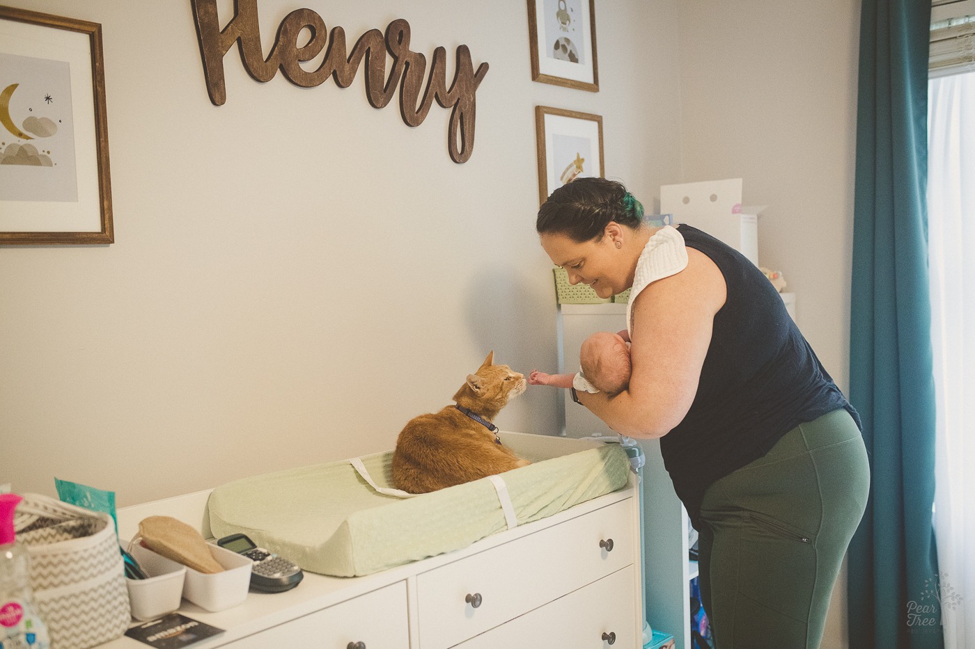 Mom talking to the orange tabby cat on her newborn son's changing pad