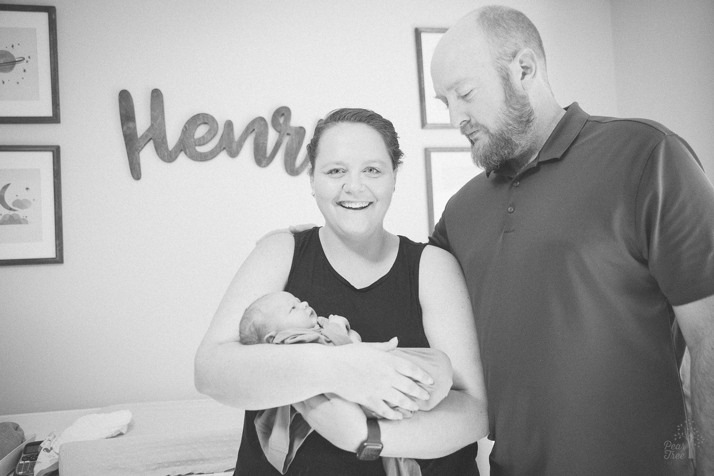 Black and white photograph of new parents holding their baby son in the nursery