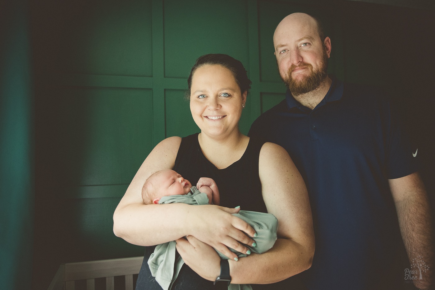 photograph of smiling parents during their newborn photography session holding their baby