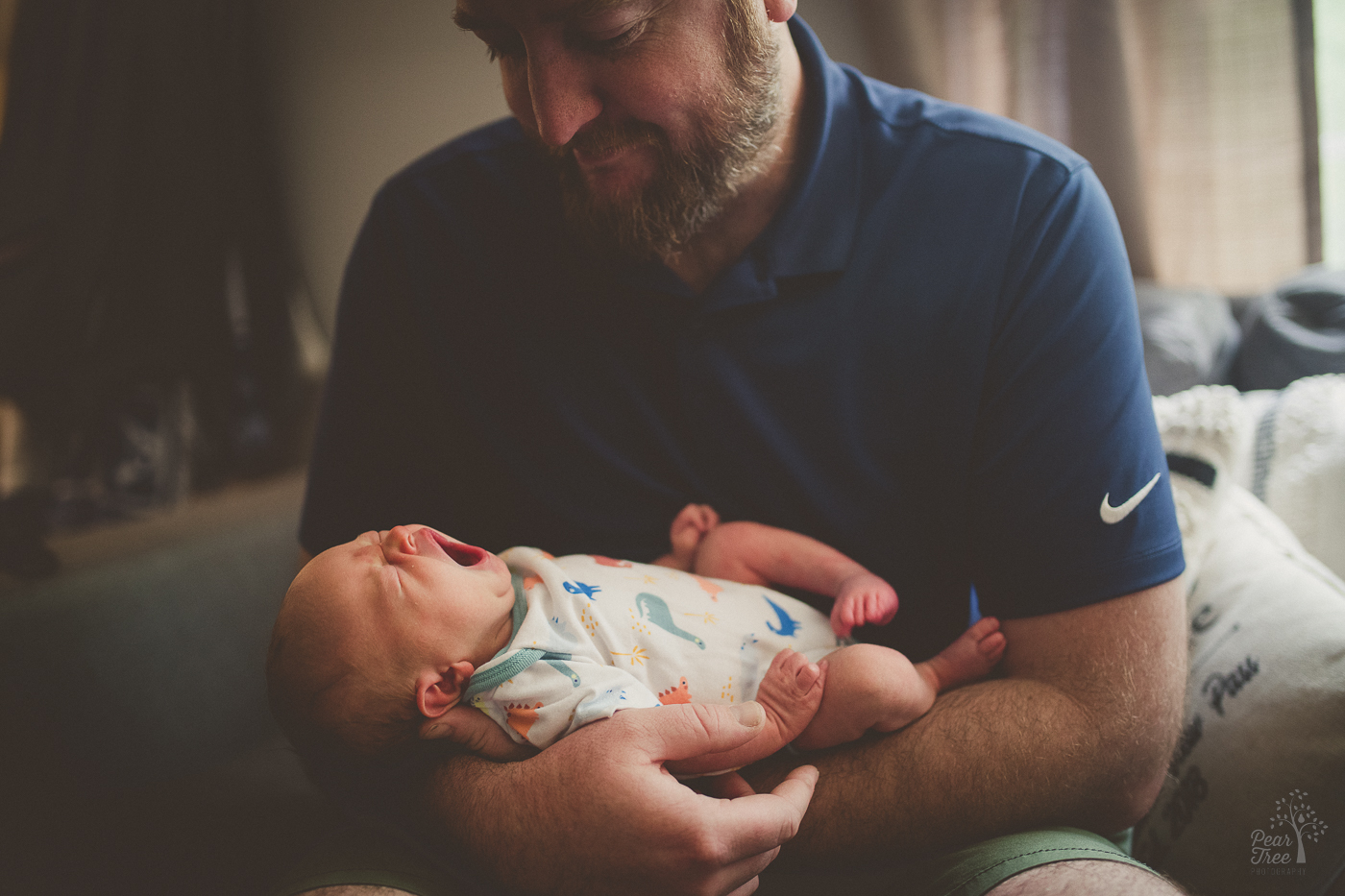 Bearded dad holding his newborn and yawning son