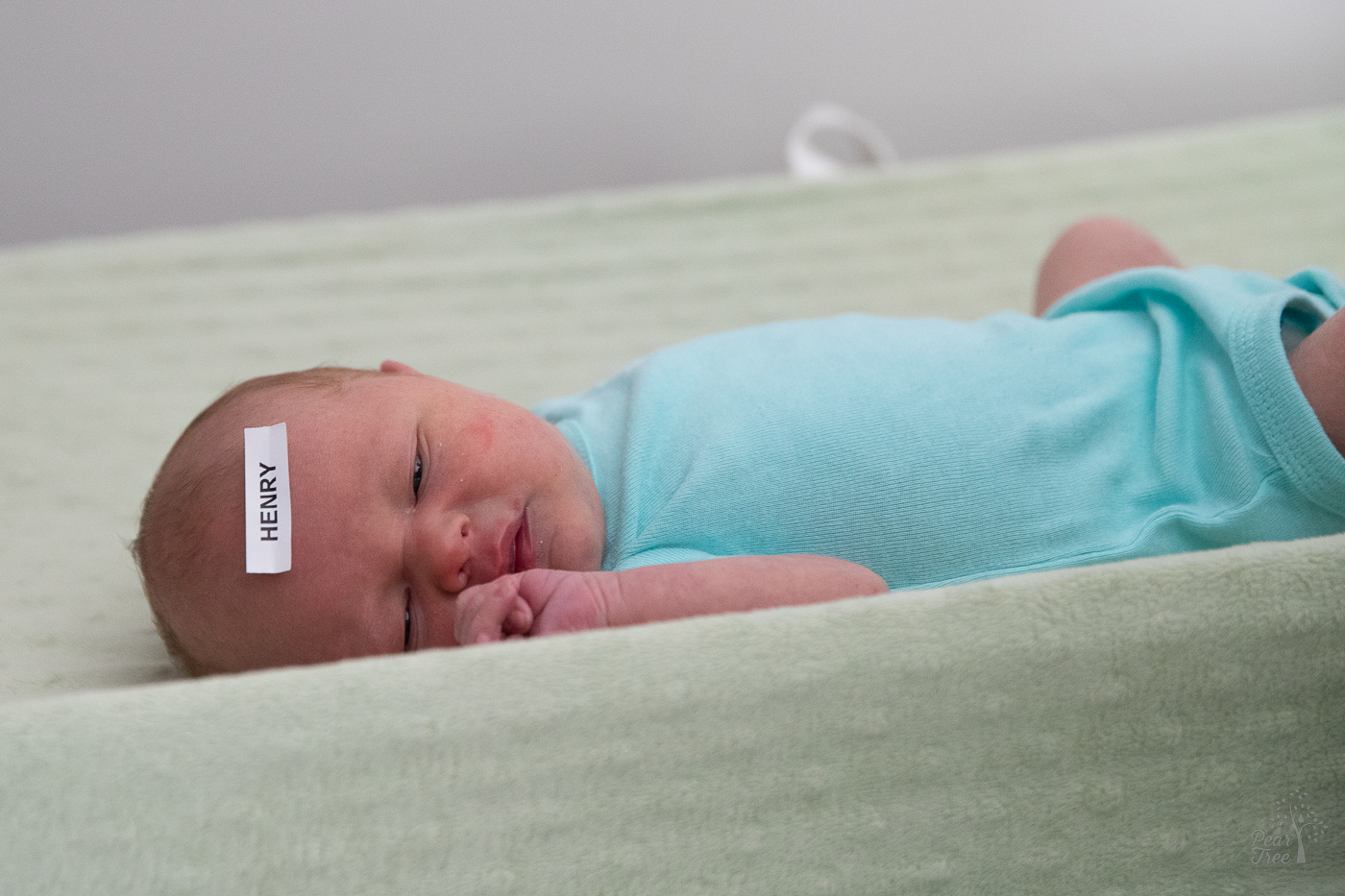 Newborn baby boy with a label of his name Henry stuck to his forehead