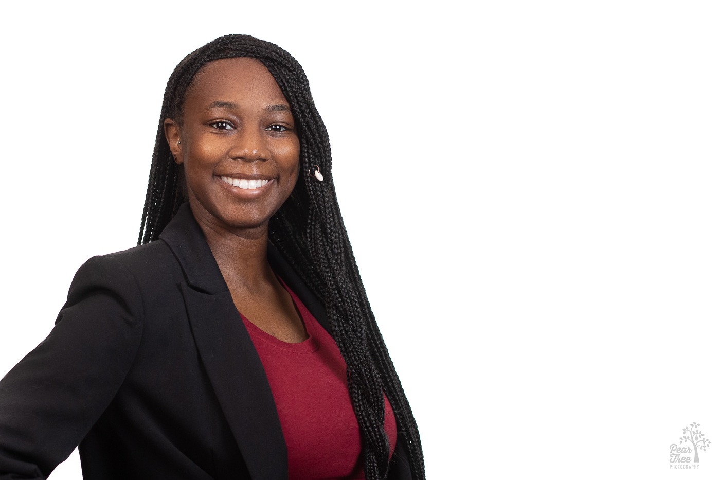 Gorgeous black woman wearing a red blouse, black blazer, and waist length braids smiling for her professional headshots in Atlanta at Covenant House Georgia