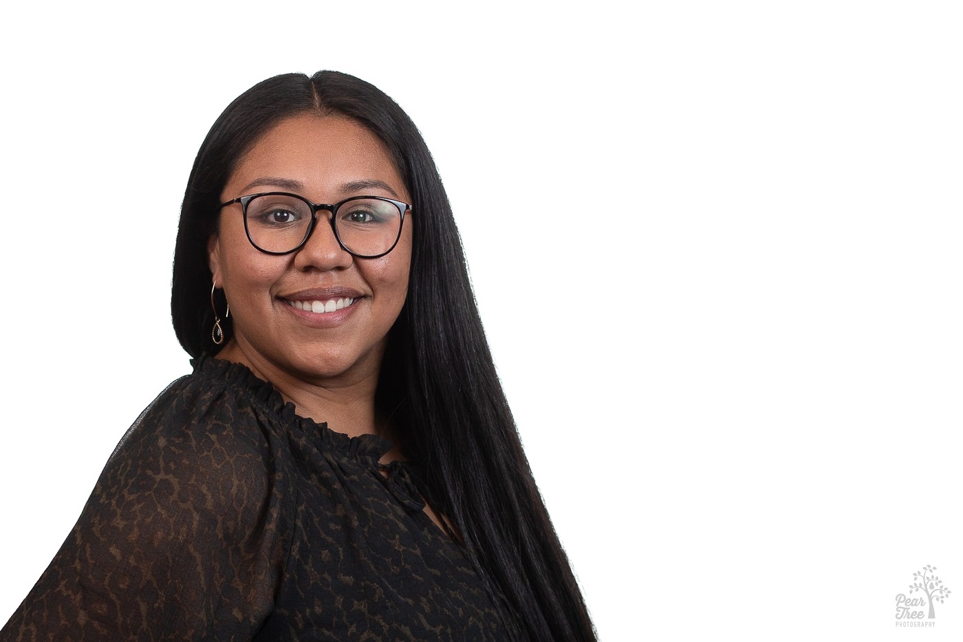 Attractive African American woman with long, straightened hair wearing a lacy black blouse and glasses is smiling for a professional headshot in Atlanta